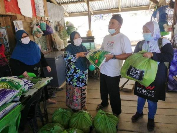 Raja Shamri (kanan) menyerahkan sumbagan kepada penduduk kampung yang ditemuinya pada Khamis.