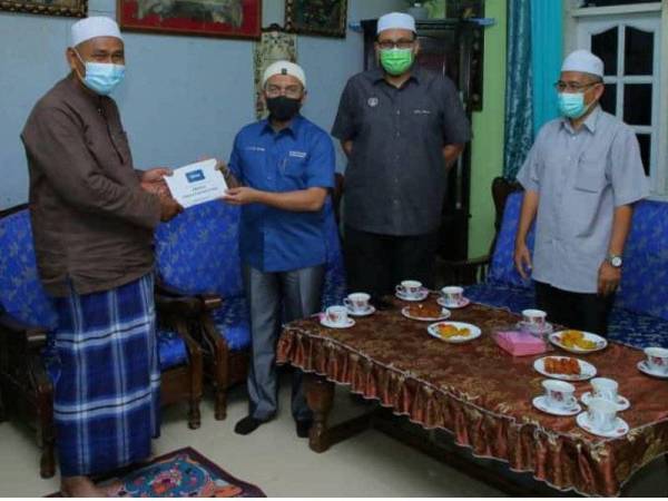 Khairil Nizam menyampaikan sumbangan kepada ayah Allahyarham Muhammad Adib di Kuala Kedah pada Jumaat.