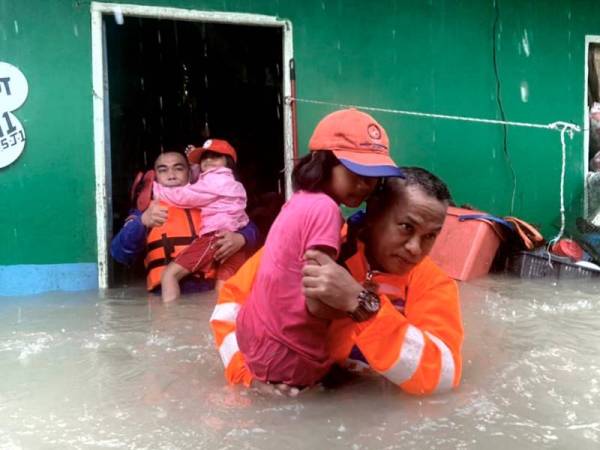 Anggota Angkatan Pertahanan Awam Malaysia (APM) memindahkan penduduk yang terjejas banjir di Kampung Sinar Budi di Batu Kawa pada Jumaat. - Foto Bernama