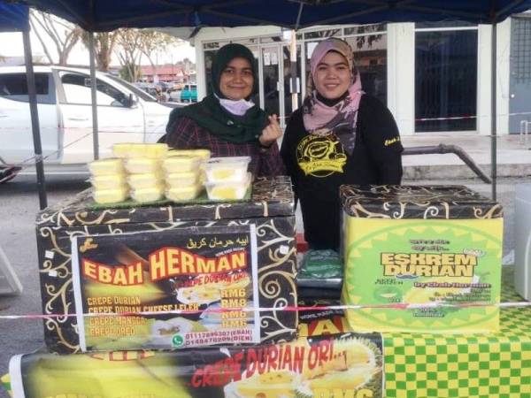 Norhabibah (kanan) tidak sangka produk yang diketengahkan dengan jenama Eskrem Durian D24 by Ebah Herman itu akan mendapat permintaan ramai termasuk FAMA yang turut memasarkannya di House of Durian FAMA di Jerantut. - Foto Facebook Ebah Herman