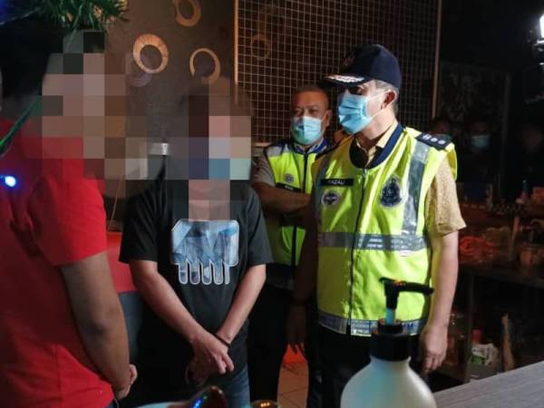 Razali (kanan) ketika operasi yang dijalankan di sebuah kedai judi di Jalan Kenari 3, Puchong pada Jumaat.