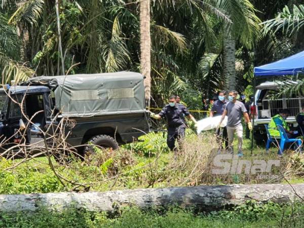 Anggota polis mengangkat mayat lelaki dipercayai warga asing yang ditemukan dalam sebuah tong air di ladang kelapa sawit di Tiga Kongsi Simpang Ampat pada Ahad.