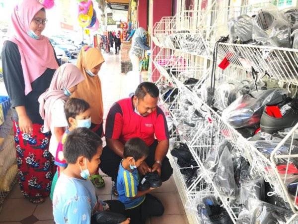 Muhammad Firdaus dan isteri memilih kasut sekolah untuk anak mereka di sebuah kedai pakaian di Sungai Besar, Selangor pada Selasa.