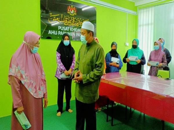 Ahmad Fadhli mendengar luahan Wan Khadijah (kiri) ketika menyampaikan sumbangan bantuan kepada mangsa-mangsa tebing runtuh dari zon merah di Pusat Khidmat Ahli Parlimen Pasir Mas di Kasar, Pasir Mas.