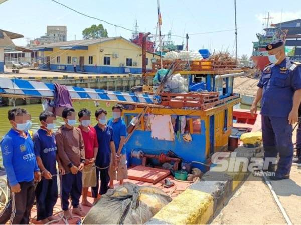 Muhd Nur Sham Asmawie (kanan) memeriksa nelayan warga Vietnam yang ditangkap menceroboh masuk ke perairan negara ini secara haram di Jeti Maritim Tok Bali, Pasir Puteh pada Selasa.