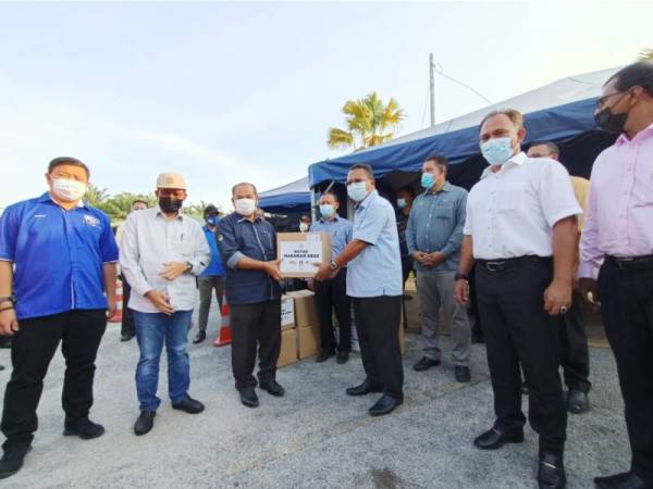 Sham (kiri) membuat serahan bantuan kotak makanan kepada Kamarulzaman di pekarangan Penjara Tapah pada Rabu.