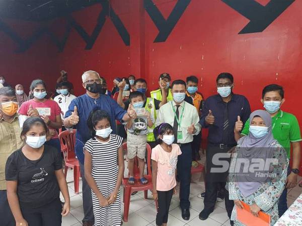 Mahfuz (tiga dari kiri) bersama penerima sumbangan keperluan sekolah di pasar raya Econsave Pokok Sena pada Khamis.