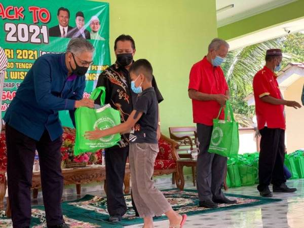 Keterangan gambarMohd Hasany (kiri) ditemani Zulkepli (dua dari kiri) menyampaikan sumbangan kelengkapan sekolah kepada salah seorang penerima di Dewan Budaya Dato' Zul Wisma, Kota Bharu pada Sabtu.