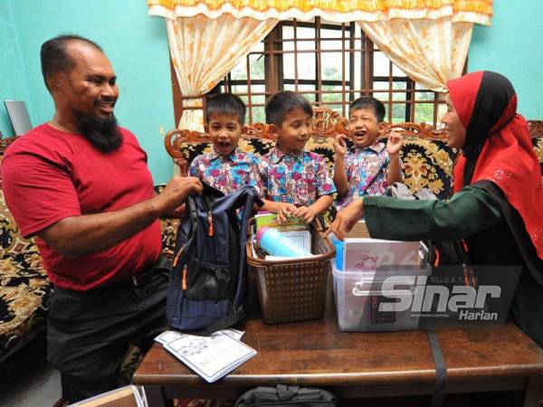 Abdul Razak (kiri) dan Susilawati (kanan) membantu mengemas buku tiga anaknya di rumah mereka di Kampung Melayu Raya, Pekan Nanas.