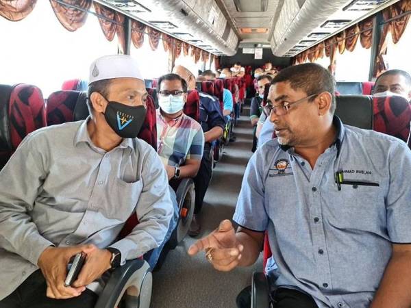 Ahmad Ruslan (kanan) berbincang dengan Sabri ketika menaiki bas persiaran di Pantai Murni, Yan pada Ahad.