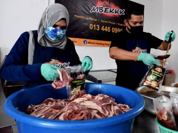 Rosnizam (kanan) dan Roazian (kiri) giat menyiapkan kambing dan ayam perap yang diusahakan. - Foto Bernama