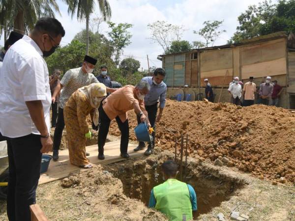 Al-Sultan Abdullah (tiga dari kiri) bersama Tunku Azizah (dua dari kiri) berkenan mencurah simen di dalam tapak rumah baharu ketika berangkat mencemar duli meninjau rumah penduduk Kampung Lompat, Temerloh hari ini. - Foto Bernama