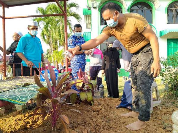 Wan Mohd Hafizam menyiram pusara Mohd Afiq sebaik selesai pengebumian di Tanah Perkuburan Islam Masjid Al-Barakah Tikam Batu, Kedah.