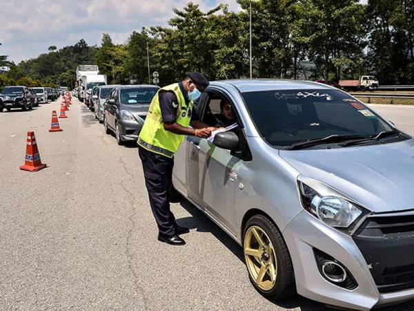 Anggota polis memeriksa dokumen perjalanan para pemandu ketika menjalankan sekatan jalan raya dalam tempoh PKP 2.0 di Plaza Tol Gombak hari ini. - Foto Bernama