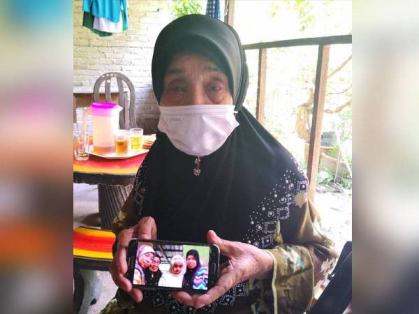 Asmah menunjukkan gambar kenangannya bersama Allahyarham Nor Hayati (dalam gambar, kanan) yang meninggal dunia dalam kejadian runtuhan jejambat SUKE yang menimpa sebuah van ketika melalui MRR2 petang Rabu.