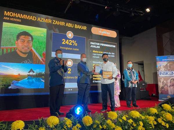 Wan Junaidi (dua dari kiri) menyampaikan anugerah kepada peserta cemerlang, Mohammad Azmir Zahir ketika majlis di Kota Bharu pada Sabtu. Mohammad Azmir mengikuti program IBBC Homestay dengan mencatatkan RM5,642.63 purata hasil jualan.