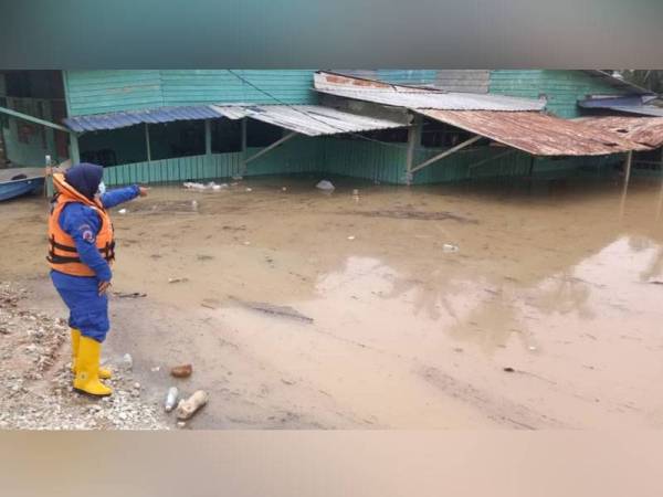 Seorang anggota APM meninjau paras air banjir di salah sebuah kampung yang dilanda banjir kilat di Kuala Selangor pada Ahad.