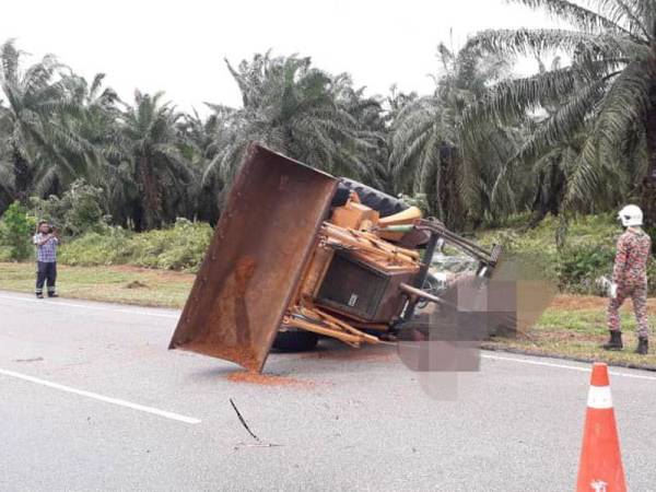 Pemandu jengkaut yang tersepit selepas jengkaut dipandunya terbalik Simpang Lima, Seri Sulong pada Ahad.- Foto Ihsan Bomba