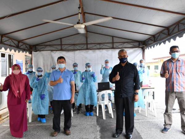 Yuserrie (depan, dua dari kanan) bersama Mansor (depan, dua dari kiri) menyantuni petugas barisan hadapan UMP yang membantu proses kemasukkan pelajar ke kampus UMP pada Sabtu.