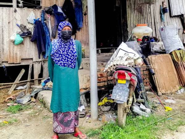 Rokiah berada di hadapan rumah usang yang didiami bersama 11 penghuni sejak 30 tahun lalu di Kampung Padang Bemban. - Foto Bernama