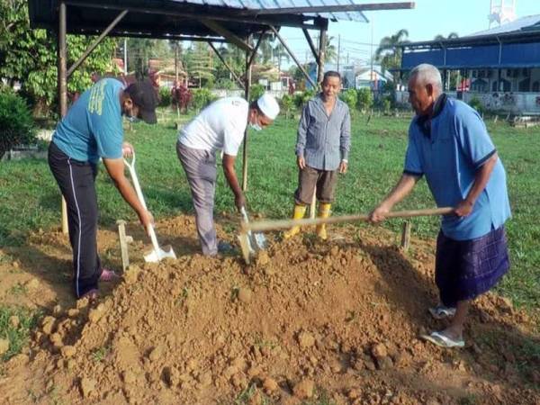 Kariah masjid dan penduduk setempat meratakan tanah kubur mangsa di Tanah Perkuburan Islam Kampung Telaga, Hulu Terengganu pada Rabu.