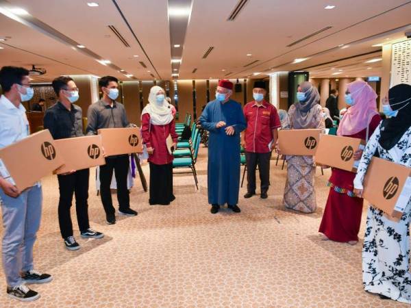 Zulkifli (tengah) beramah mesra bersama pelajar asnaf UTM yang menerima sumbangan komputer riba pada majlis penyerahan sumbangan itu di Menara Tabung Haji hari ini. - Foto Bernama