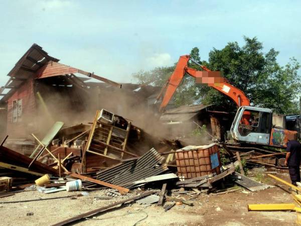 Kerja-kerja merobohkan kilang kayu dan papan, stor penyimpanan serta kediaman pekerja dilakukan dalam Operasi Penguatkuasaan Pencerobohan Tanah Kerajaan di Jalan jeti, Pelabuhan Klang pada Khamis. - Foto Bernama