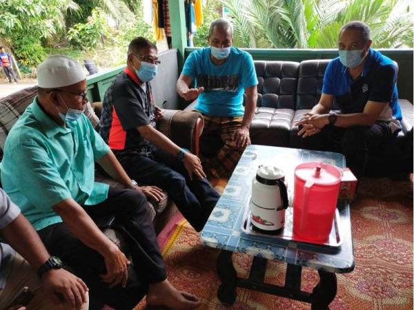 Hanafiah (dua dari kiri) bersama pengarah JKM negeri (kanan)bertanya khabar dengan bapa arwah (dua dari kanan) di kediaman keluarga mangsa di Kampung Telaga, Hulu Terengganu pada Khamis.