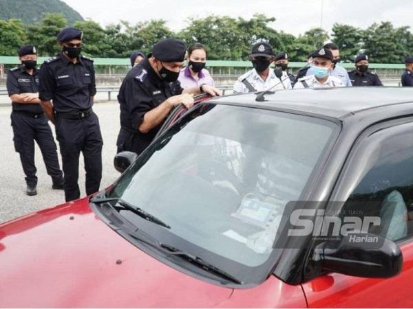 Mior Faridalathrash memeriksa salah sebuah kenderaan yang melalui SJR Ipoh Selatan pada Jumaat.