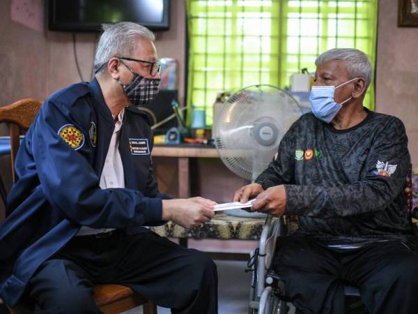 Ismail Sabri (kiri) ketika menyampaikan sumbangan kepada Md Salleh pada Majlis Penyerahan Sumbangan kepada Veteran ATM sempena Program Cakna Veteran ATM di Alor Setar hari ini. - Foto Bernama