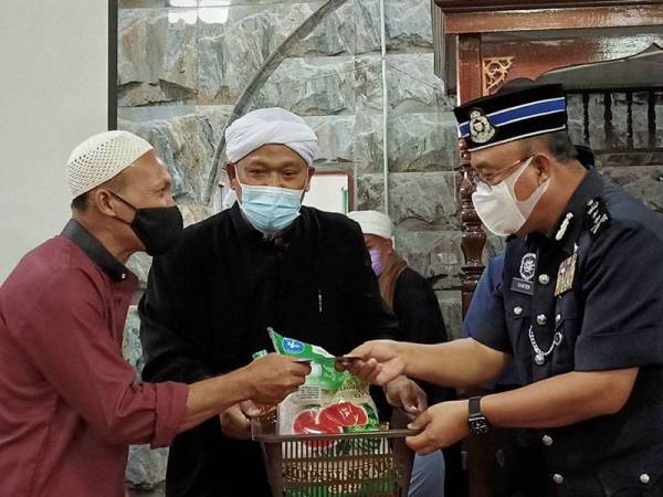 Shafien (kanan) menyampaikan sumbangan kepada penduduk pada Program Kunjungan Mahabbah di Masjid Mukim Permatang Sungkai, Pasir Puteh pada Jumaat.