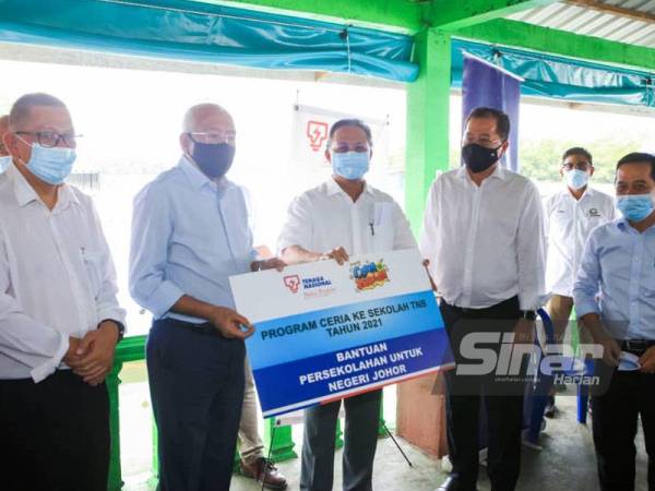 Mahdzir Khalid (dua dari kiri) melakukan simbolik penyerahan bantuan persekolahan untuk Johor kepada Hasni (tengah) di Restoran Seri Pantai, Iskandar Puteri pada Ahad.