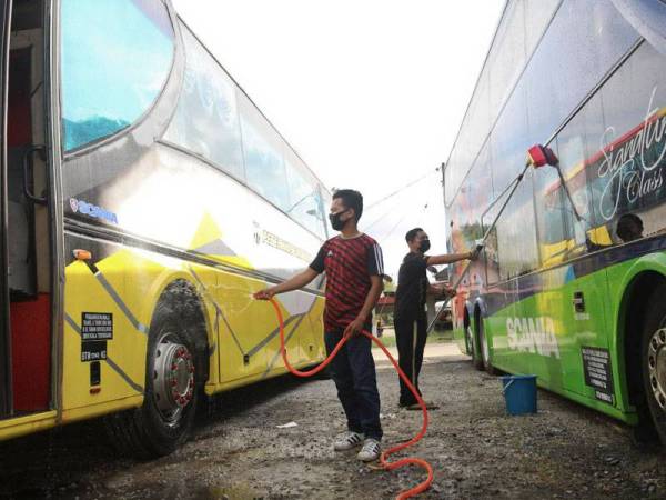 Pengusaha Bas Persiaran, Mohd Nazir Mubin Ibrahim (kiri) menyediakan dua bas ke Cameron Highlands dan Langkawi selepas syarikat basnya mula beroperasi pada Rabu di Kampung Gong Pauh, Kuala Terengganu.