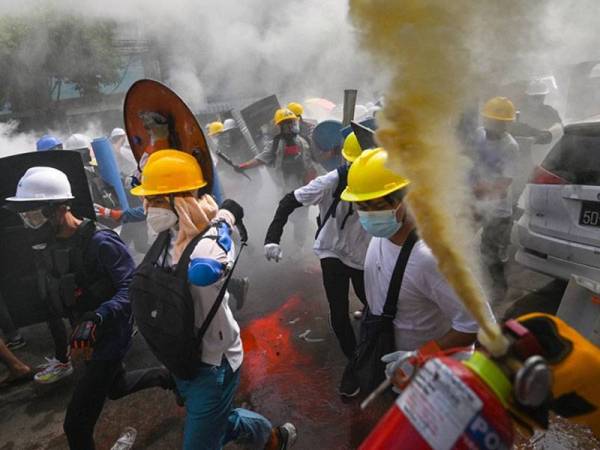 Gambar fail menunjukkan seorang penunjuk perasaan menggunakan alat pemadam api ketika rakan-rakannya melarikan diri akibat pasukan keselamatan melepaskan gas pemedih mata di Yangon. - Foto AFP