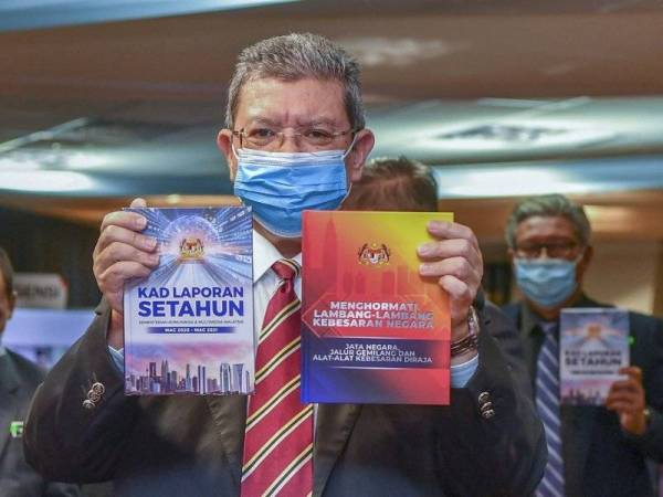 Saifuddin menunjukkan Buku Menghormati Lambang-lambang Kebesaran Negara dan Kad Laporan Setahun KKMM selepas pelancaran buku tersebut di KKMM, Putrajaya pada Selasa. - Foto Bernama