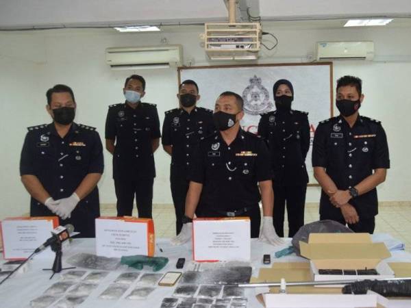 Mohd Haki (depan, tiga dari kanan) bersama sebahagian dadah yang dirampas susulan penahanan ketiga lelaki dalam serbuan di tiga lokasi berasingan di Kemaman pada Ahad dan Isnin.