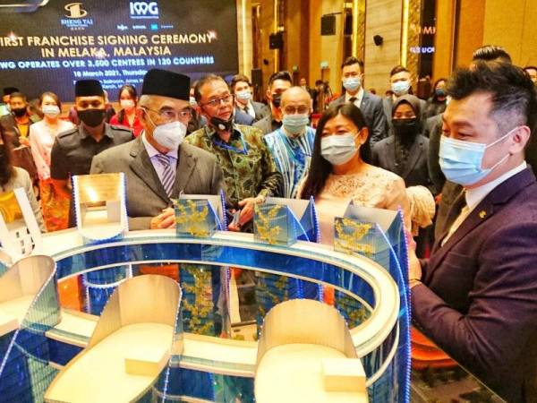 Sir Ley (tengah) mengiringi Mohd Ali (kiri) melihat model perancangan projek The Sail Melaka yang akan dilengkapi ruang kerja fleksibel ketika majlis menandatangani perjanjian di antara Sheng Tai International dan IWG di Hotel Ames Ayer Keroh, Melaka pada Khamis.