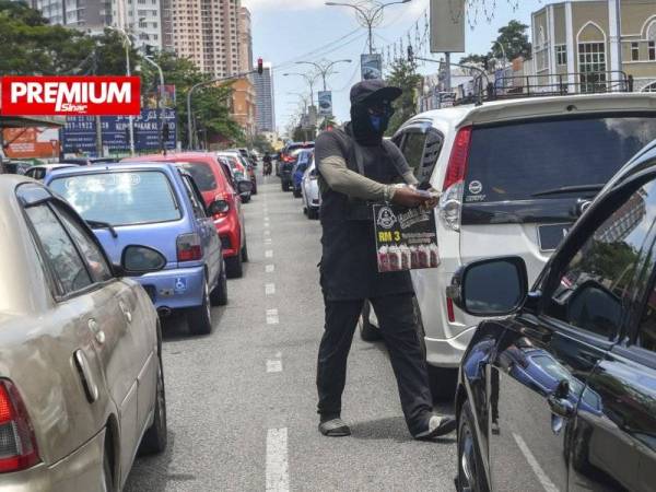 Kelihatan peniaga giat menjalankan penjualan makanan dan minuman kepada pengguna jalan raya yang melalui kawasan persimpangan lampu isyarat meskipun terdedah dengan keadaan bahaya. - Foto Bernama