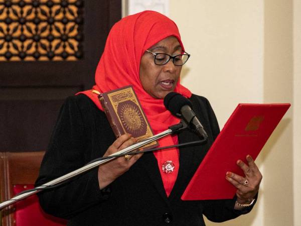 Samia Suluhu Hassan memegang al-Quran semasa mengangkat sumpah sebagai presiden pertama wanita di Pejabat Presiden di Dar es Salaam. - Foto AFP