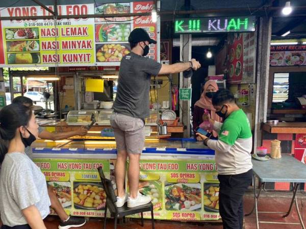 Rizuam (kanan) ketika rakaman video dan temubual oleh vlogger antarabangsa di medan selera sebuah pasar raya di Kuala Terengganu pada Jumaat.