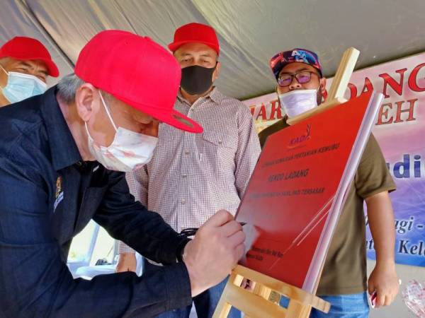 Kamarudin turunkan tandatangan sebagai simbolik perasmian Hari Ladang Peringkat Jajahan Pasir Puteh dianjurkan KADA di Bendang Tok Ajam, Selising pada Sabtu.