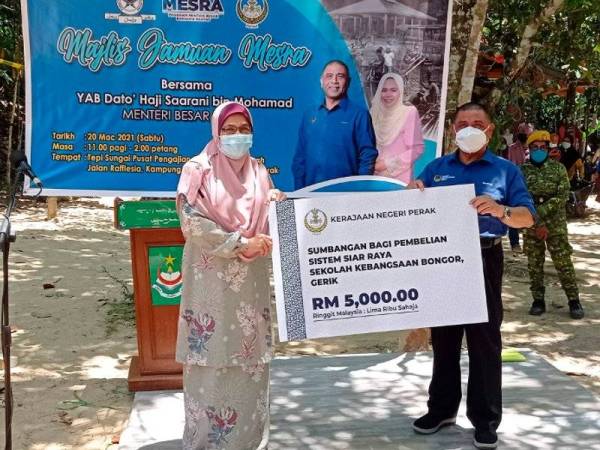 Saarani Mohamad (kanan) menyerahkan replika cek kepada guru Sekolah Kebangsaan Kampung Bongor Normawati Abdul Aziz (kiri) pada majlis Jamuan Mesra sempena Program Menteri Besar Bersama Rakyat (Mesra) di Kampung Bongor, Bersia, dekat sini hari ini. - Foto Bernama