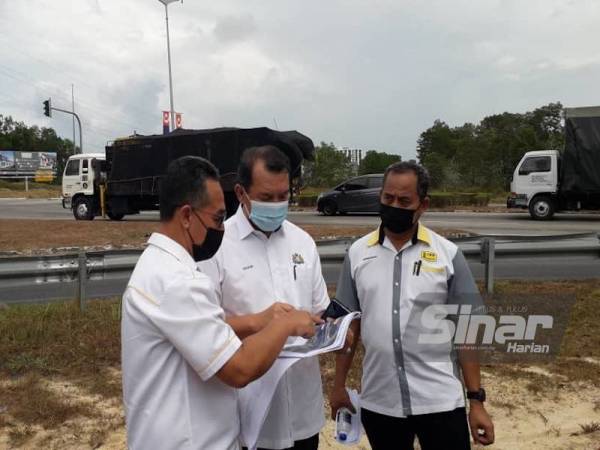 Mohd Solihan (tengah) melihat pelan Tapak Projek Pembinaan Directional Ramp Persimpangan Lebuhraya Senai–Desaru (SDE) di Plaza Tol Bandar Penawar, Kota Tinggi pada Isnin.