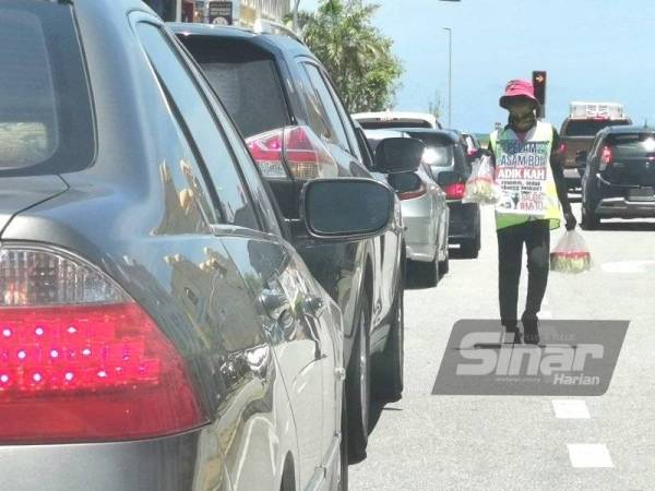 Seorang penjaja kelihatan berniaga makanan di persimpangan lampu isyarat di pusat bandar Kuala Terengganu pada Selasa.
- FOTO SINAR HARIAN/ NORHASPIDA YATIM