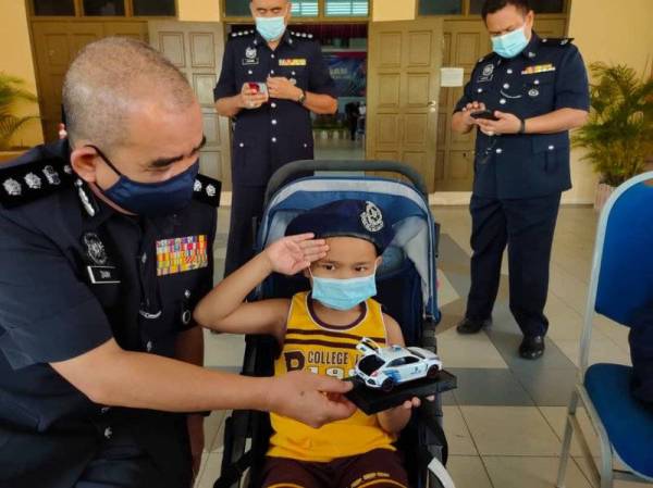 Noorzainy memakaikan beret polis kepada Muhammad Firash Arryan sebelum dibawa menaiki MPV polis.