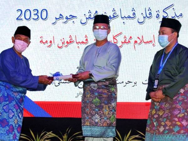 Hasni (tengah) menerima Skrol Pelan Pembangunan Mampan Johor 2021 (Hal Ehwal Agama Islam) daripada Tosrin selepas perasmian Muzakarah Pelan Pembangunan Mapan Johor 2030 di Pusat Islam Iskandar, Johor Bahru pada Khamis.