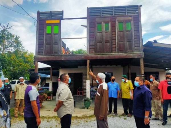 Mangsa ribut Kampung Sungai Kering, Darus Ismail,63,(dua dari kanan) menunjukkan rumahnya yang terjejas kepada Muhammad Sanusi (tiga dari kanan) pada Rabu.