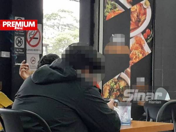 Papan tanda larangan merokok tidak diendahkan seorang pelanggan di sebuah kedai makan di Johor Bahru.