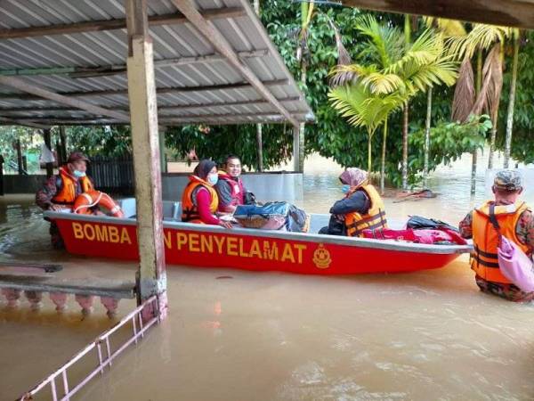 Anggota bomba membantu memindahkan mangsa banjir di Kampung Pandan 2 di sini selepas banjir melanda kawasan itu pada Rabu. - Foto Ihsan JBPM Pahang)
