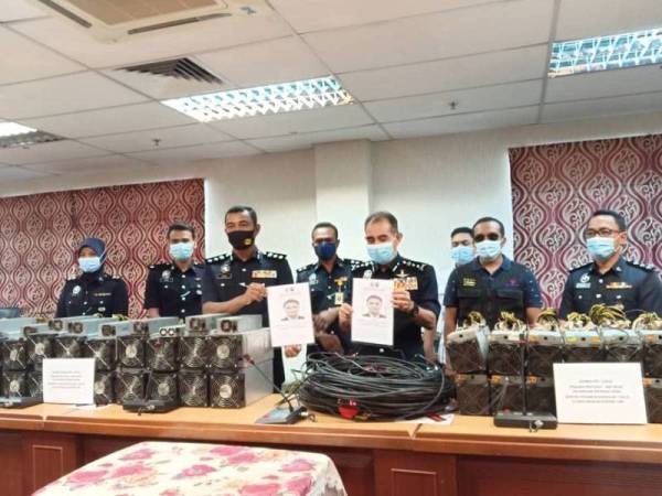 Abdul Majid (tengah) bersama mesin mining bitcoin yang dirampas pada sidang akhbar di Ibu Pejabat Polis Kontinjen (IPK) Melaka pada Jumaat.